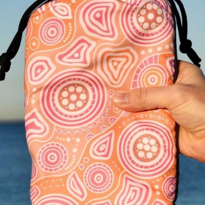Walkabout Indigenous Beach Towel folded in eco-friendly travel bag, showcasing the vibrant orange Aboriginal design with walkabout symbols and traditional patterns that connect travelers to the sacred journey and spiritual relationship with country