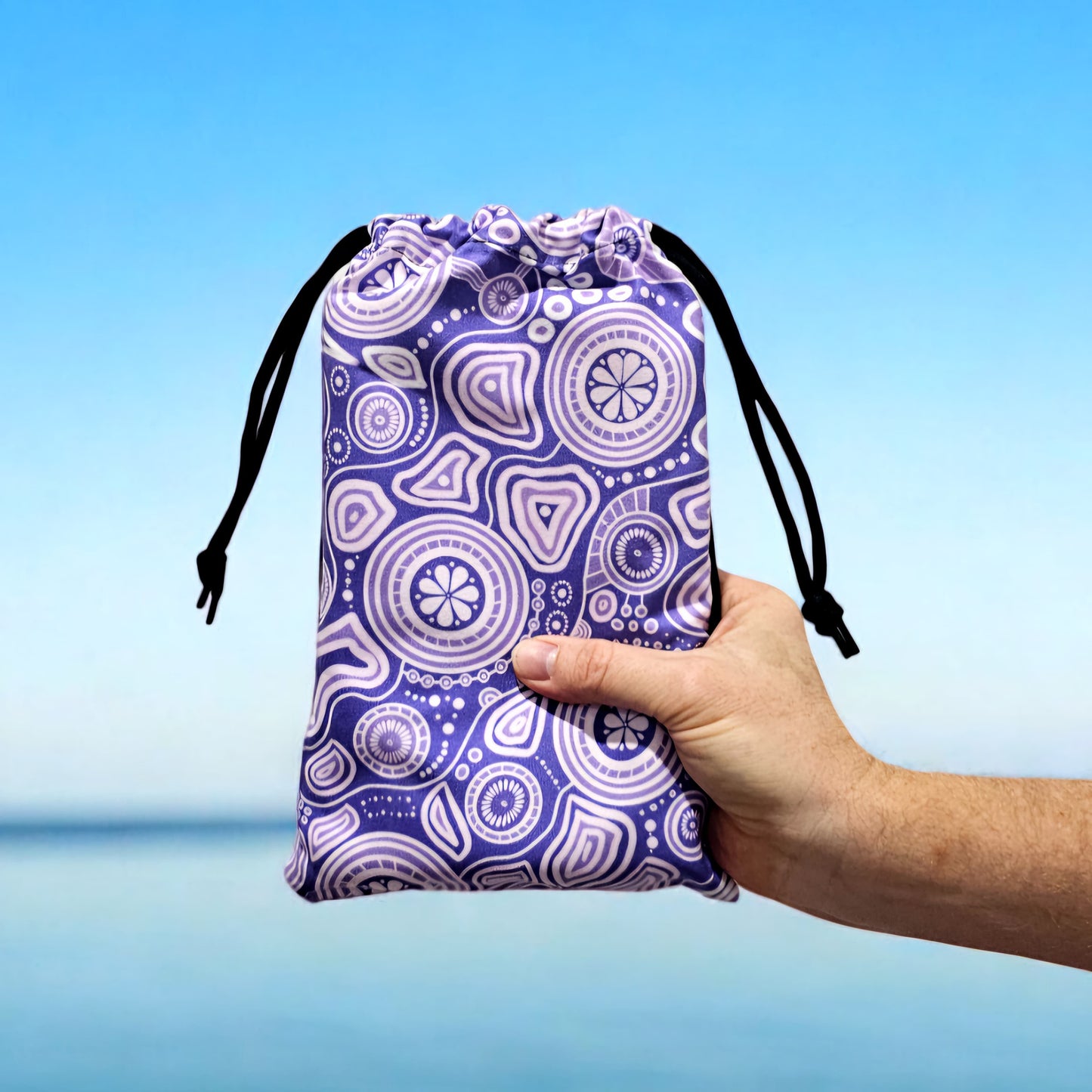 Walkabout Indigenous Travel Towel folded in compact travel bag, showcasing the deep purple Aboriginal design with walkabout symbols and traditional patterns that connect travelers to the sacred journey and spiritual relationship with country