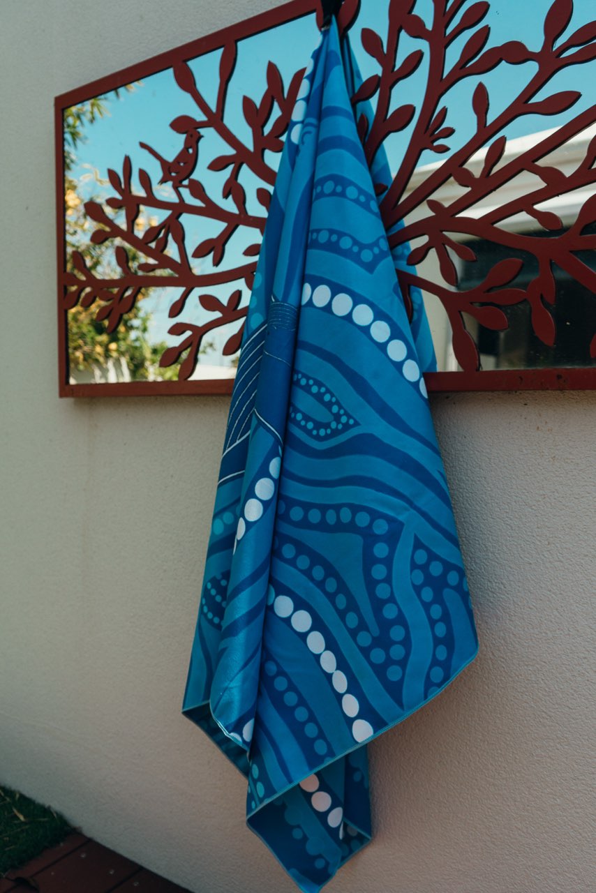 Blue towel with white patterns hanging on a decorative metal wall piece.