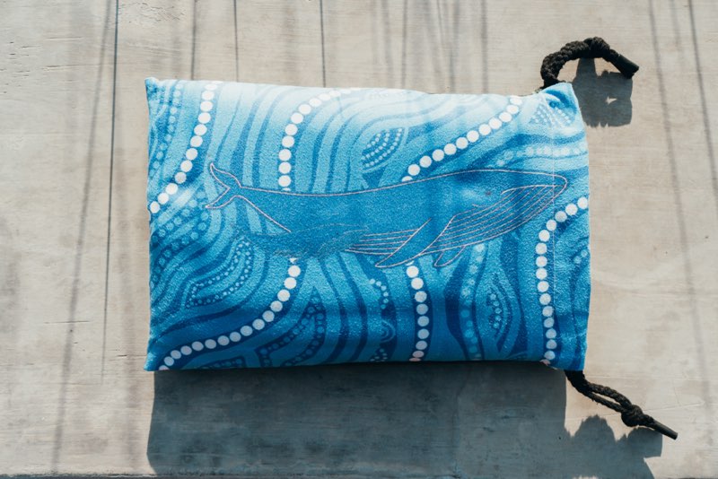 Blue fabric pouch with whale design on a wooden surface