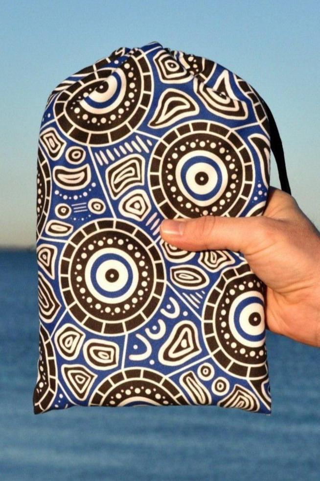 Seascape Indigenous Travel Towel folded in eco-friendly packaging, showcasing Aboriginal ocean dreamtime artwork with flowing water patterns and traditional dot work representing the spiritual connection to country and sea
