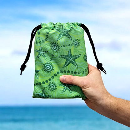 Starfish Kids Indigenous Travel Towel folded in travel bag, showcasing the vibrant green Aboriginal design with starfish symbols and traditional patterns that connect young ones to ocean dreamtime stories and coastal heritage